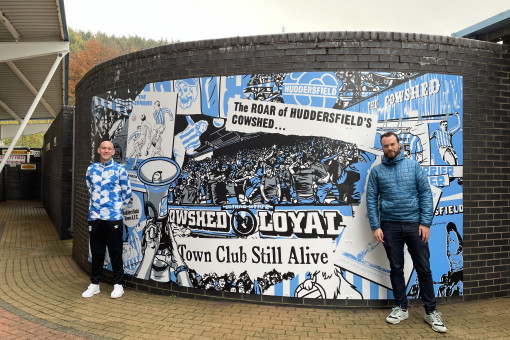 Peter O'Toole stands next to the mural he designed in the South Stand.